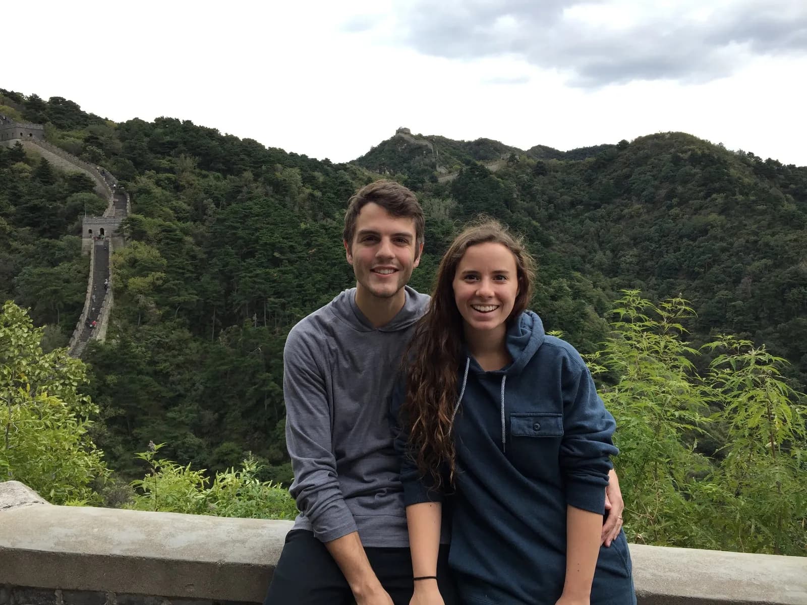 Nick and a companion with the Great Wall winding over green hills behind