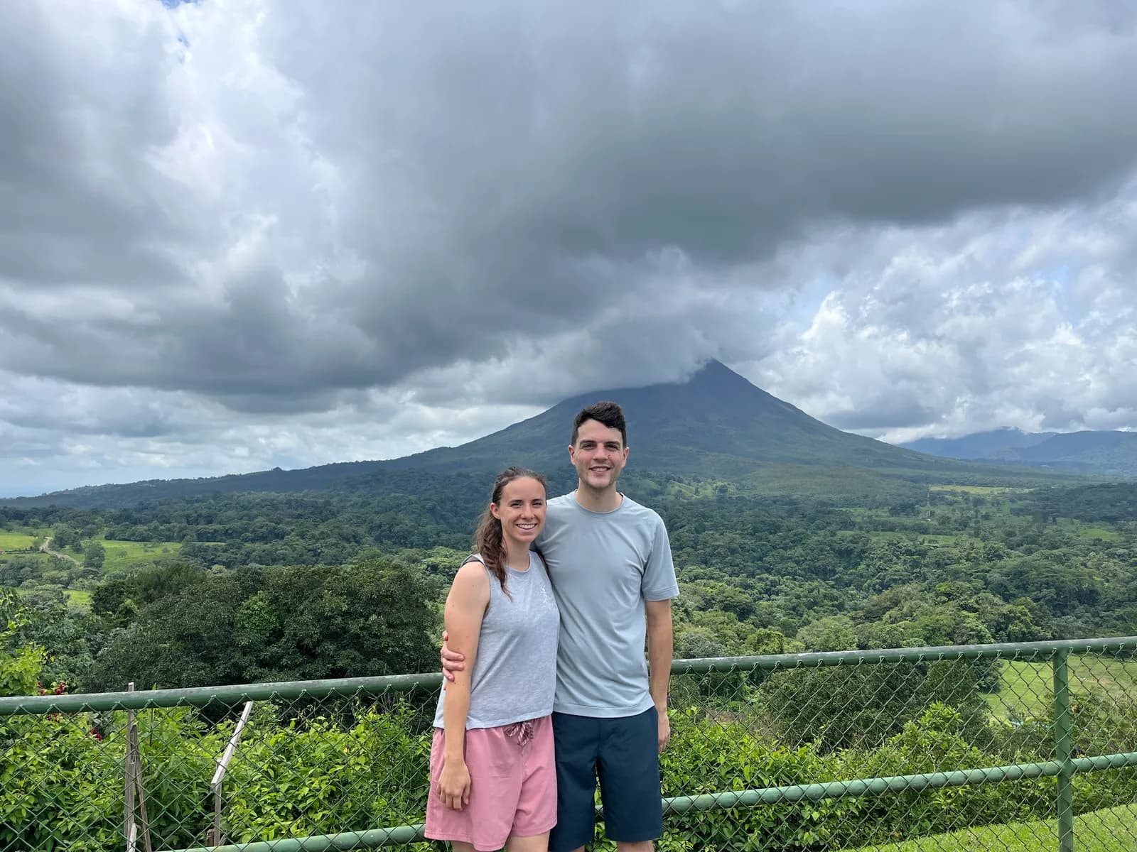 Nick and a companion in front of Arenal Volcano under heavy clouds