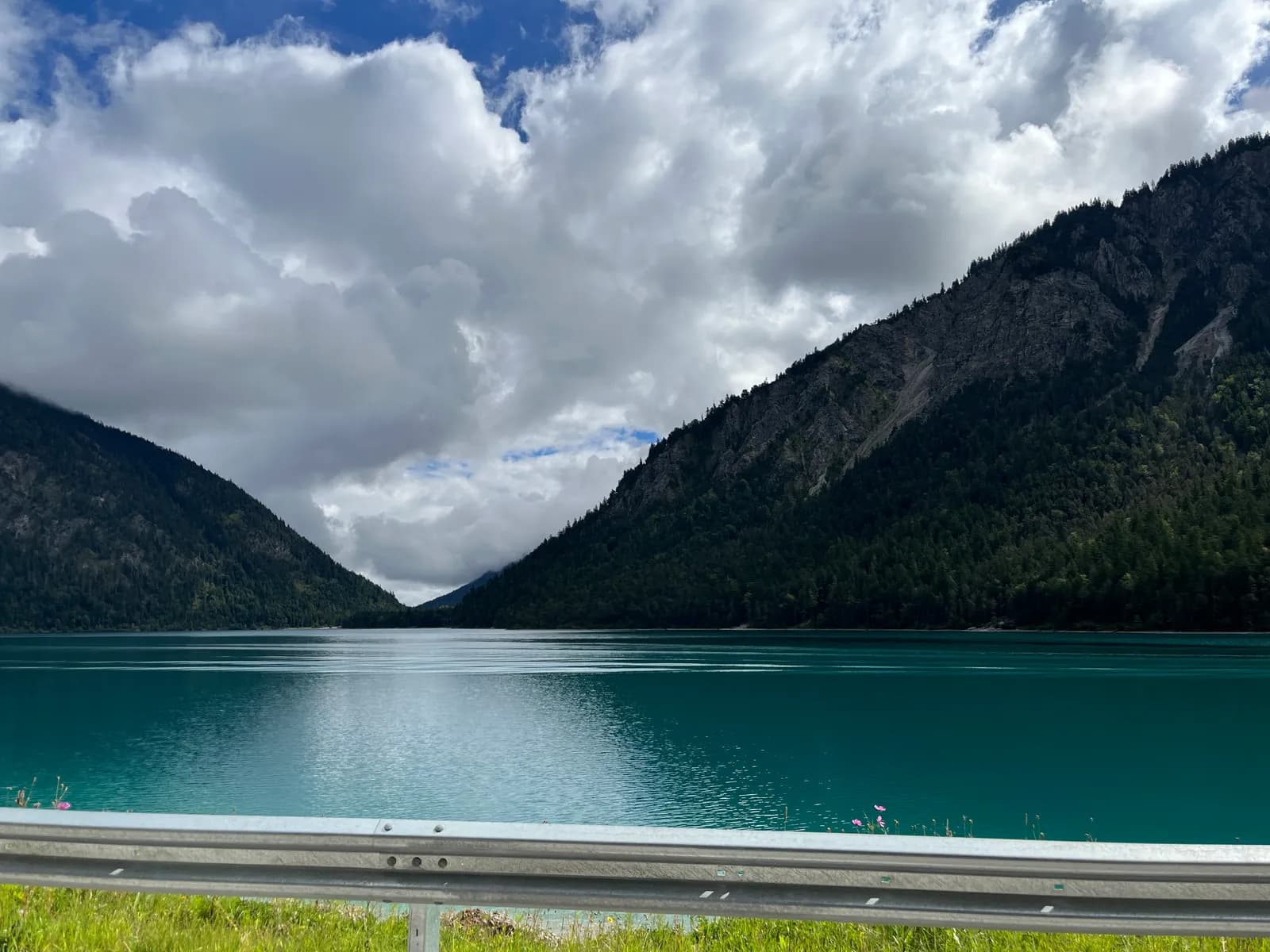 A turquoise alpine lake between steep forested mountains