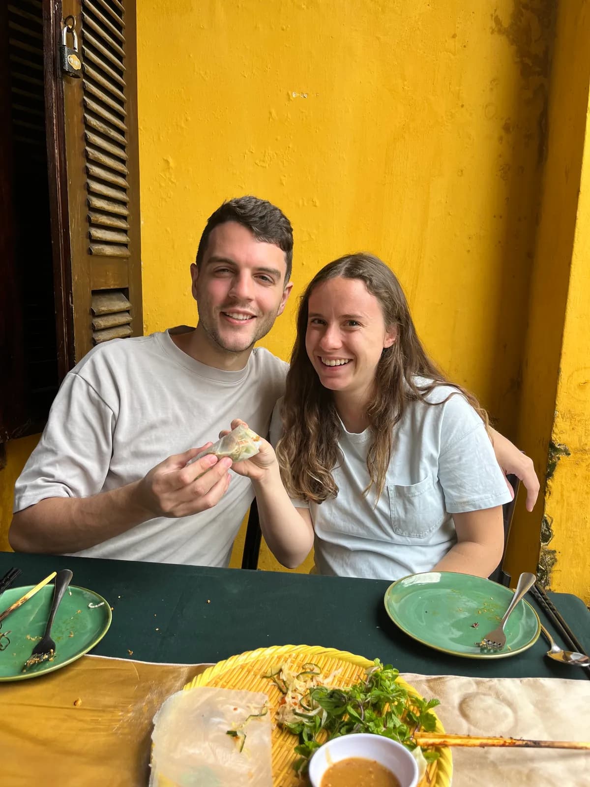 Nick and a companion at dinner against a yellow wall